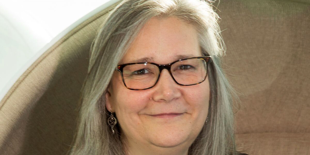 Photo of Amy Hennig grinning and wearing glasses