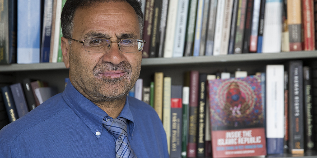 Photo of Mahmood Monshipouri in front of a bookshelf