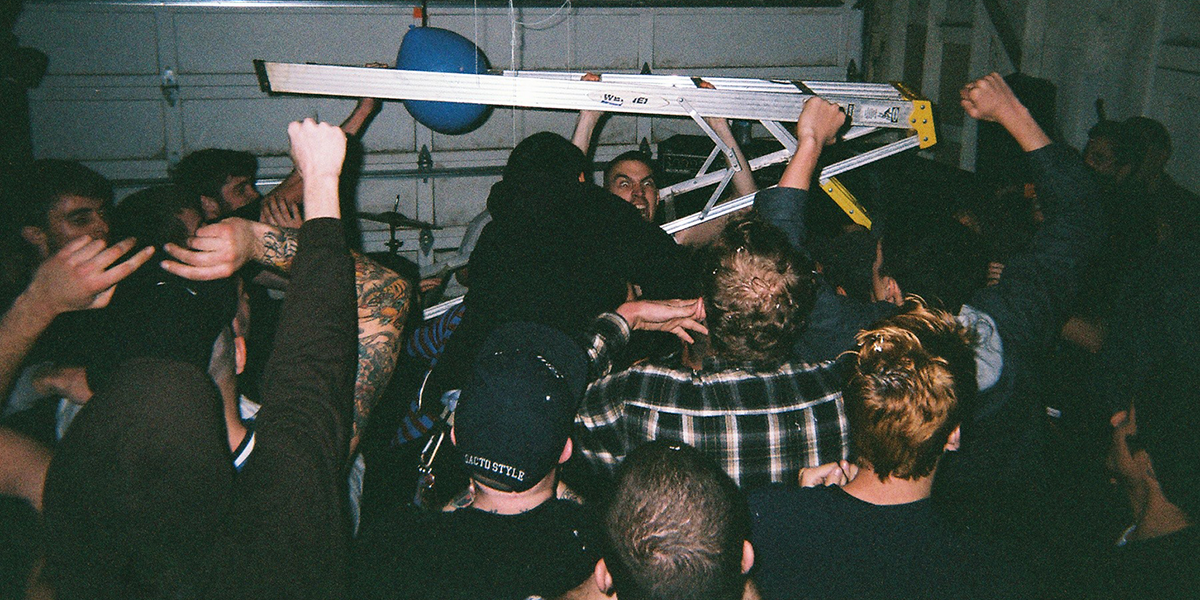 Photo of Matt Saincome and others holding ladder in mosh pit in a garage