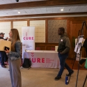 Visitors looking at posters with a table for CURE in the back