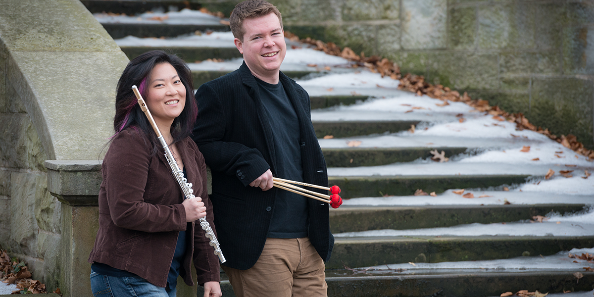 Photo of the A/B Duo holding instruments standing by snow-covered stairway