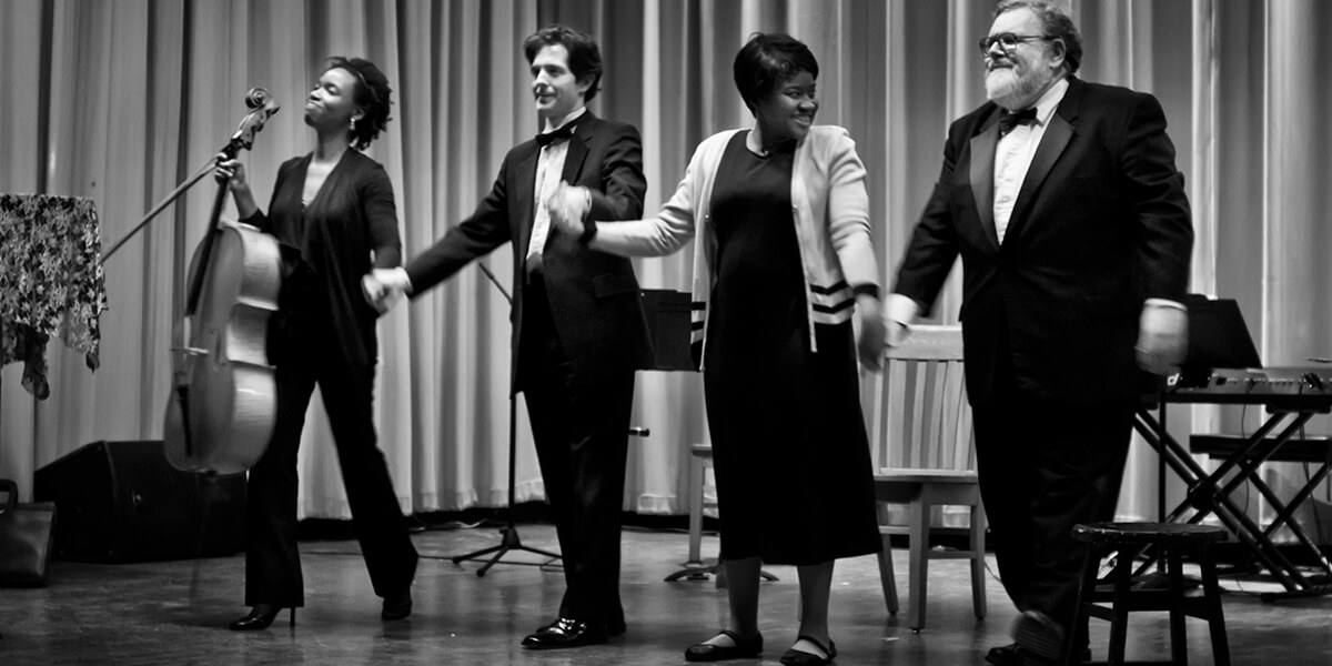Black and white photo of the Core Ensemble trio and Shinerrie Jackson taking a bow on stage
