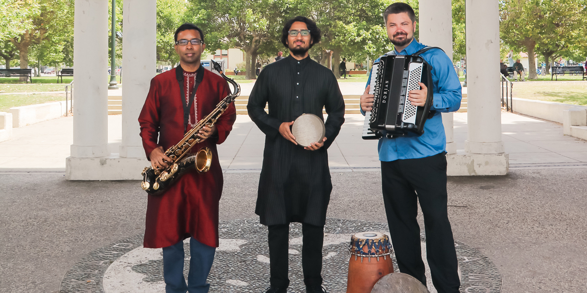 Photo of the Alaya Project trio holding their instruments standing outdoors