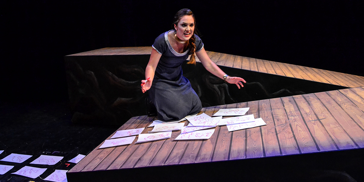 Photo of woman kneeling on wooden ramp with pieces of paper in front of her