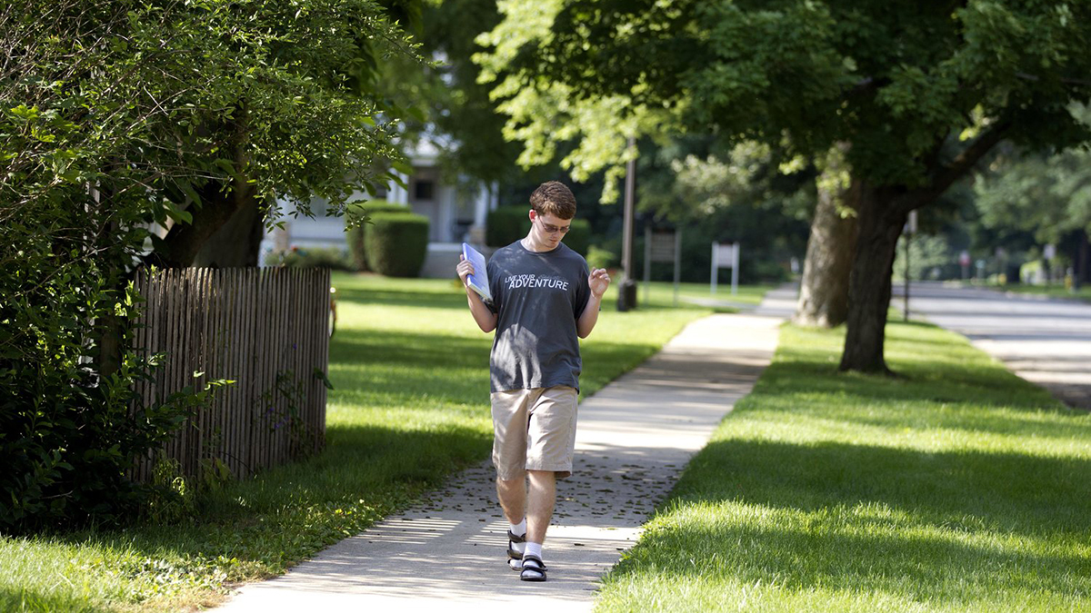 David "Deej" James Savares walking on a sidewalk holding a binder