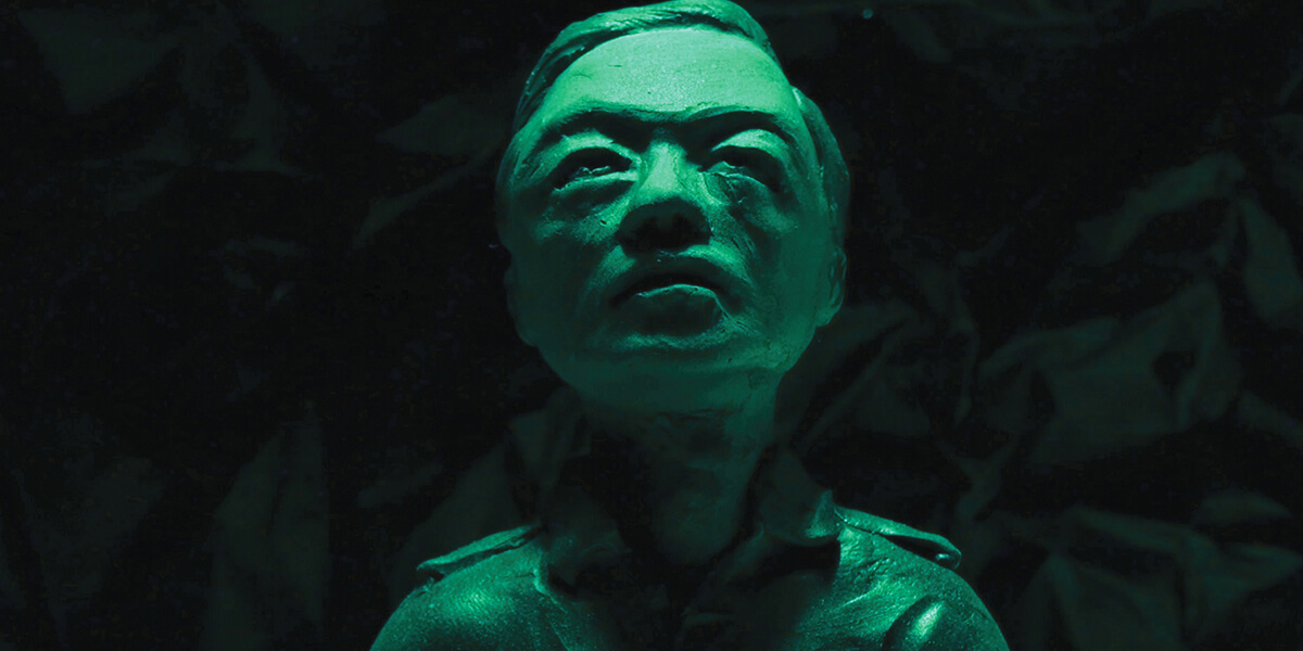 Green-tinted image of clay sculpture of Vietnamese man