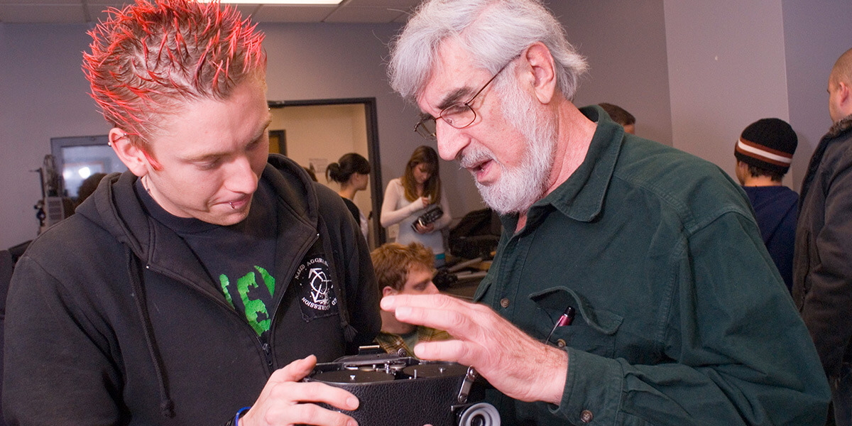 Photo of a student and Jameson Goldner looking at an analog motion-picture camera