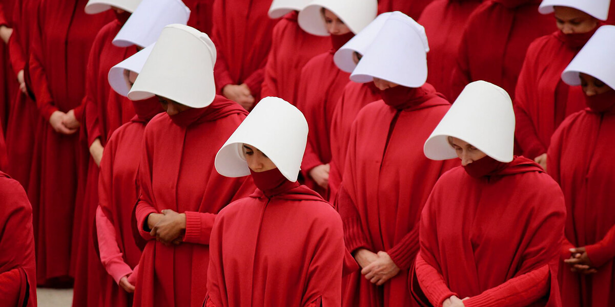 Photo of women wearing white visor sand red hoodies from The Handmaid's Tale