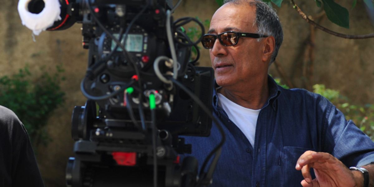 Photo of Abbas Kiarostami wearing sunglasses behind film camera