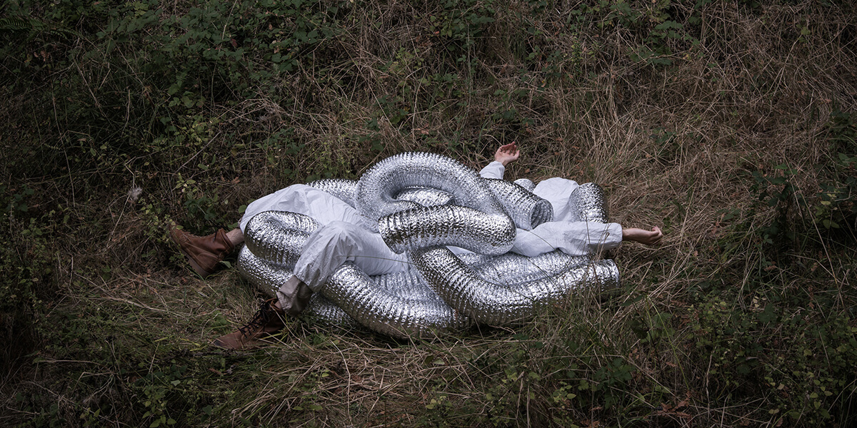 Photo by Nathan Kosta of person laying on ground surrounded by foil coil