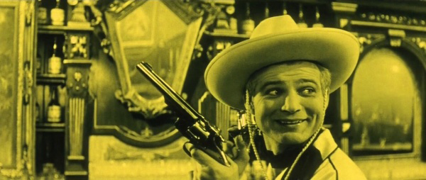 Yellow-tinted photo of Lemonade Joe holding a pistol in a saloon