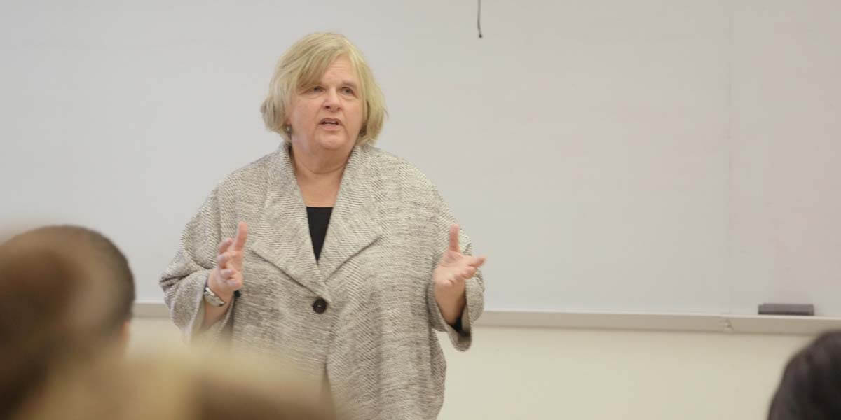 Photo of Kitty Millet lecturing in a classroom