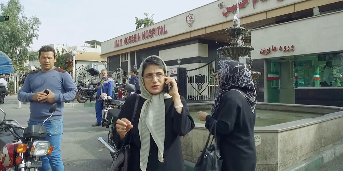 Nasrin Sotoudeh speaking on a cell phone in the parking lot of a strip mall