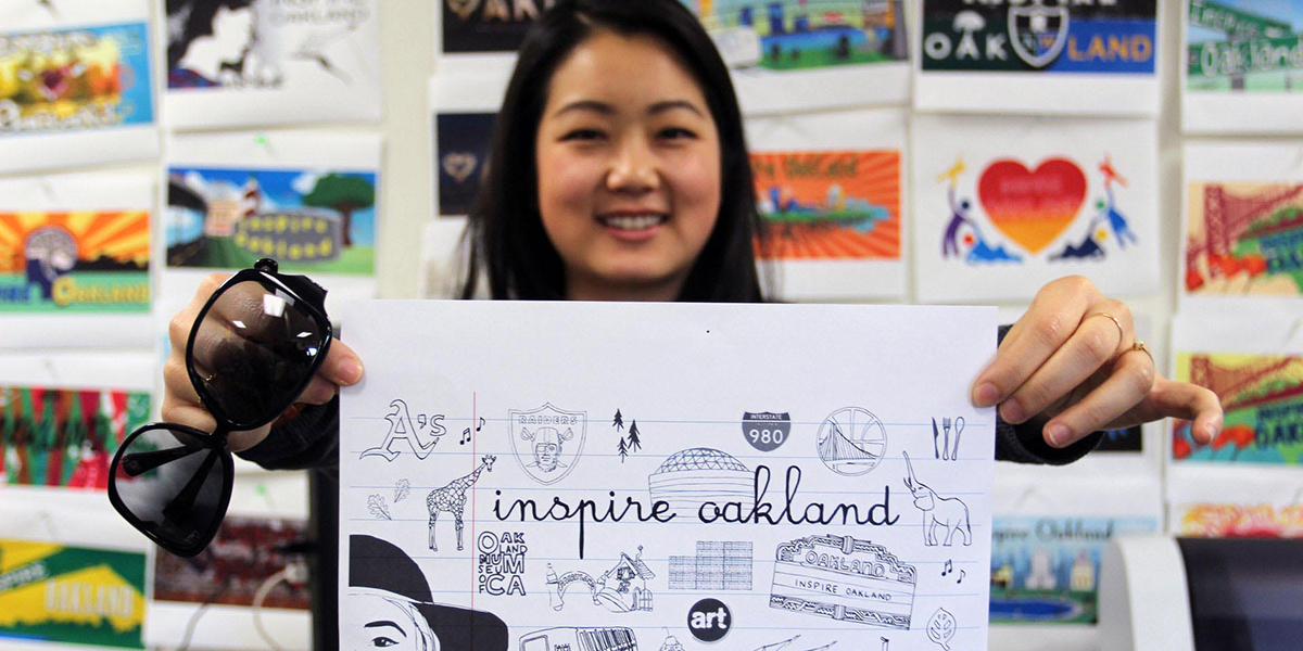 Photo of woman holding sketch with images of Oakland and the text Inspire Oakland