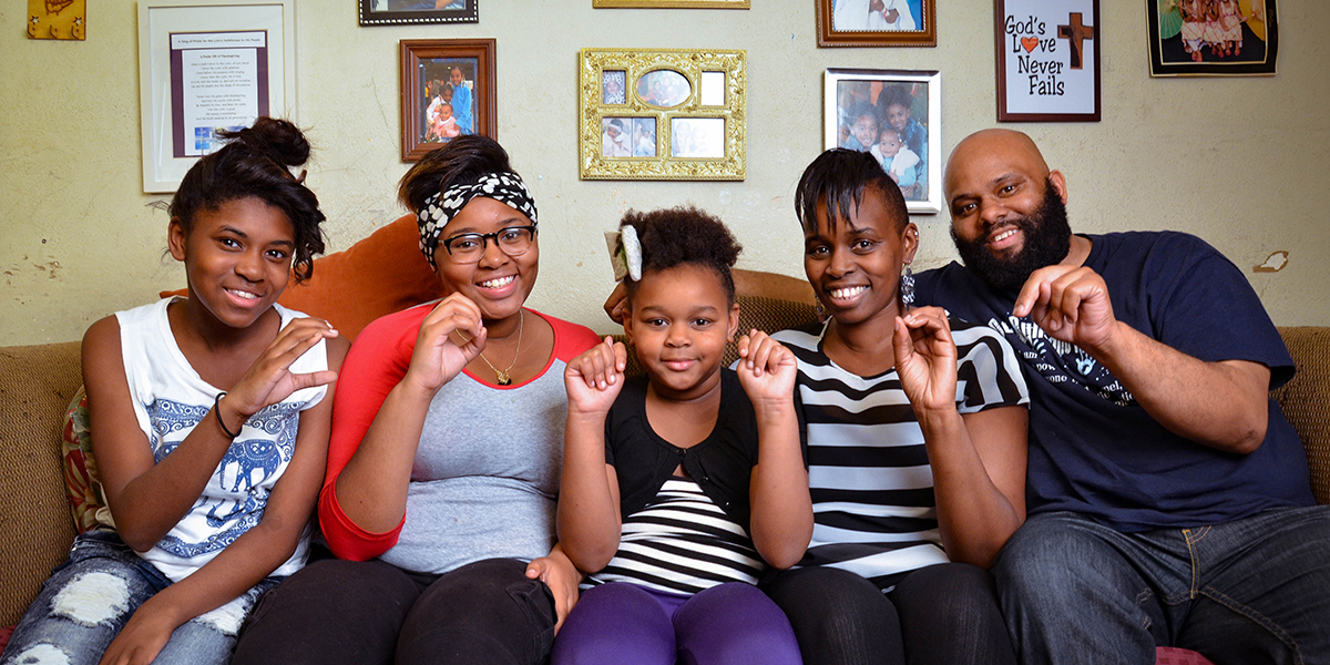 Photo of family of five using sign language while sitting on a couch