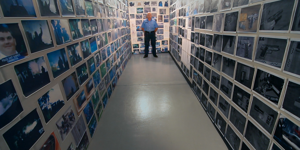 Photo of walls filled with photographs and a man at back of room