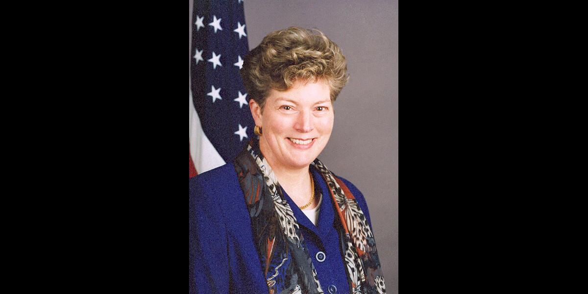 Photo of Kathleen Steven smiling in front of American flag