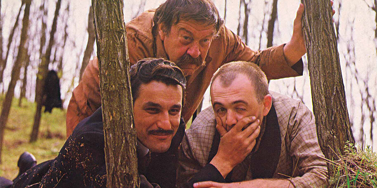 Photo of three men crouching in the woods