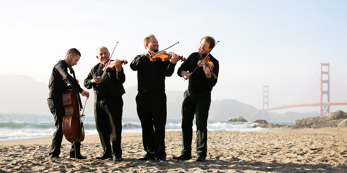 Photo of Quartet San Francisco performing on the beach near Golden Gate Bridge