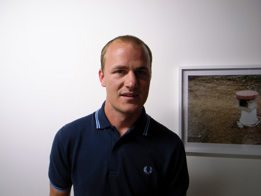Photo of Will Rogan standing in front of a framed photograph