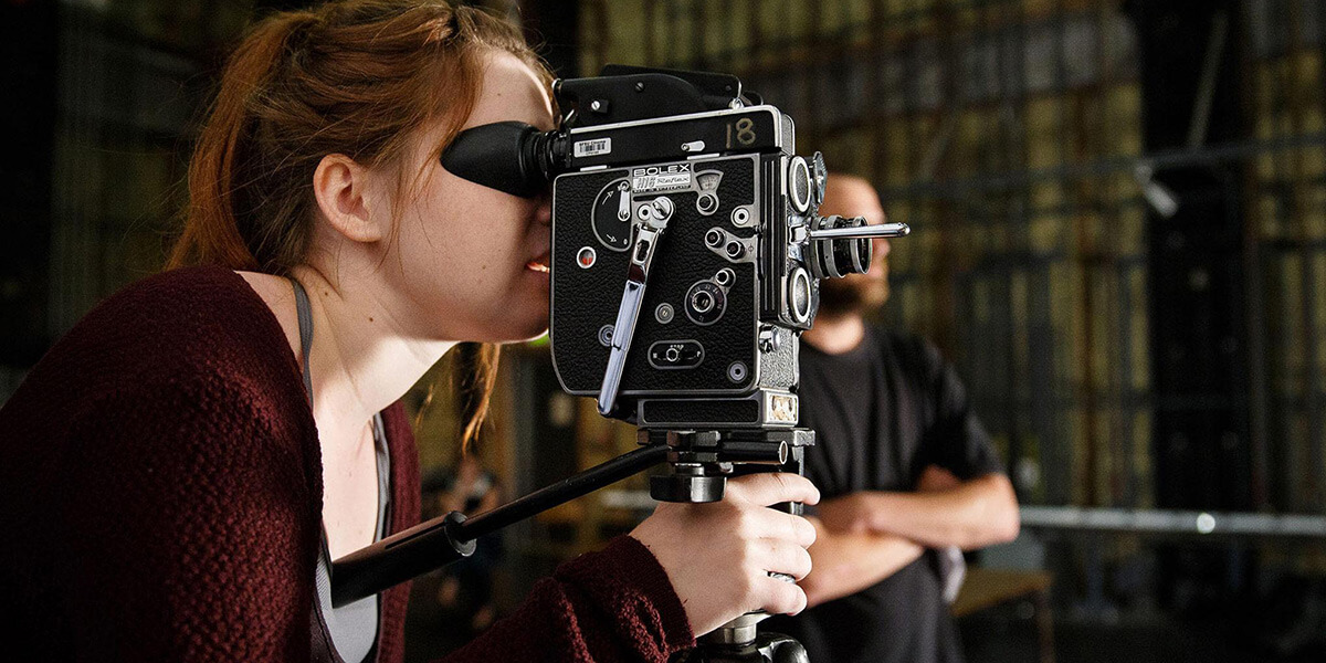 Photo of student looking through lens of Bolex camera on soundstage