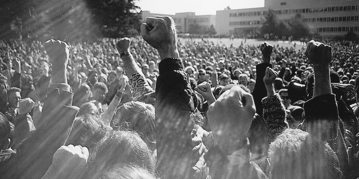 Black and white photo of hundreds of people raising their fists in the air on the SF State quad during 1968 student strike for ethnic studies