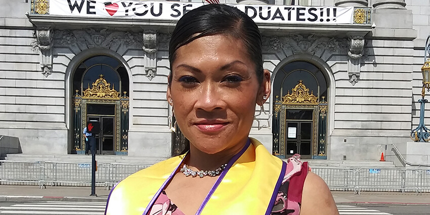 Photo of Juthaporn Chaloeicheep wearing graduation sash in front of San Francisco City Hall