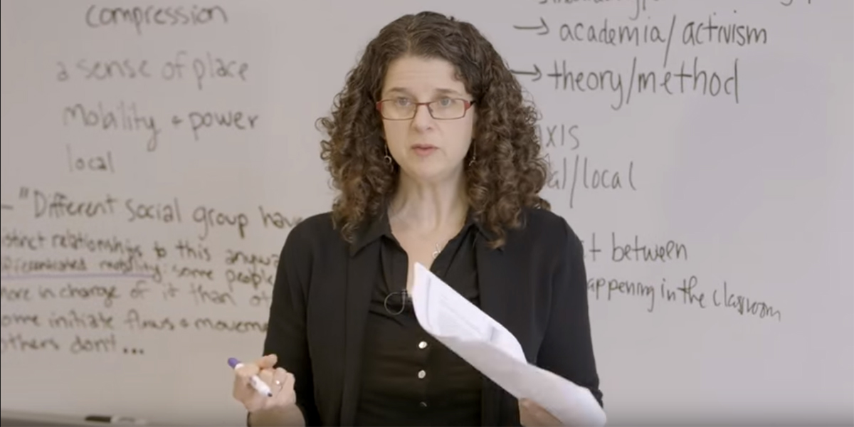 Photo of Deborah Cohler standing in front of a white board and holding a piece of paper