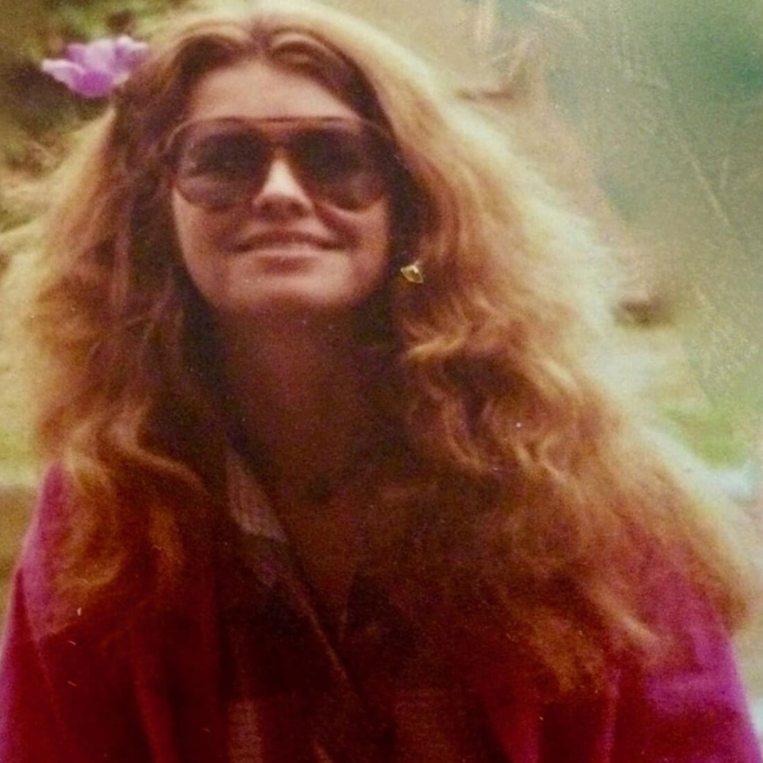 Archival photo of Yvonne Daley wearing a flower in her hair, magenta jacket and plaid shirt