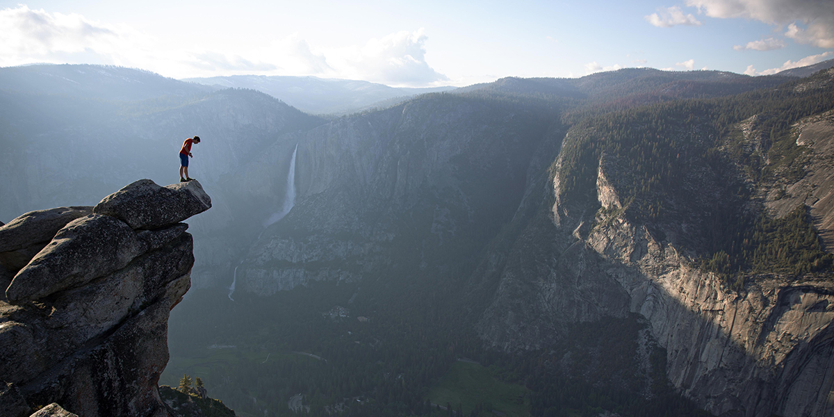 Photo of climber Alex Honnold peering over edge of Glacier Point in Yosemite National Park