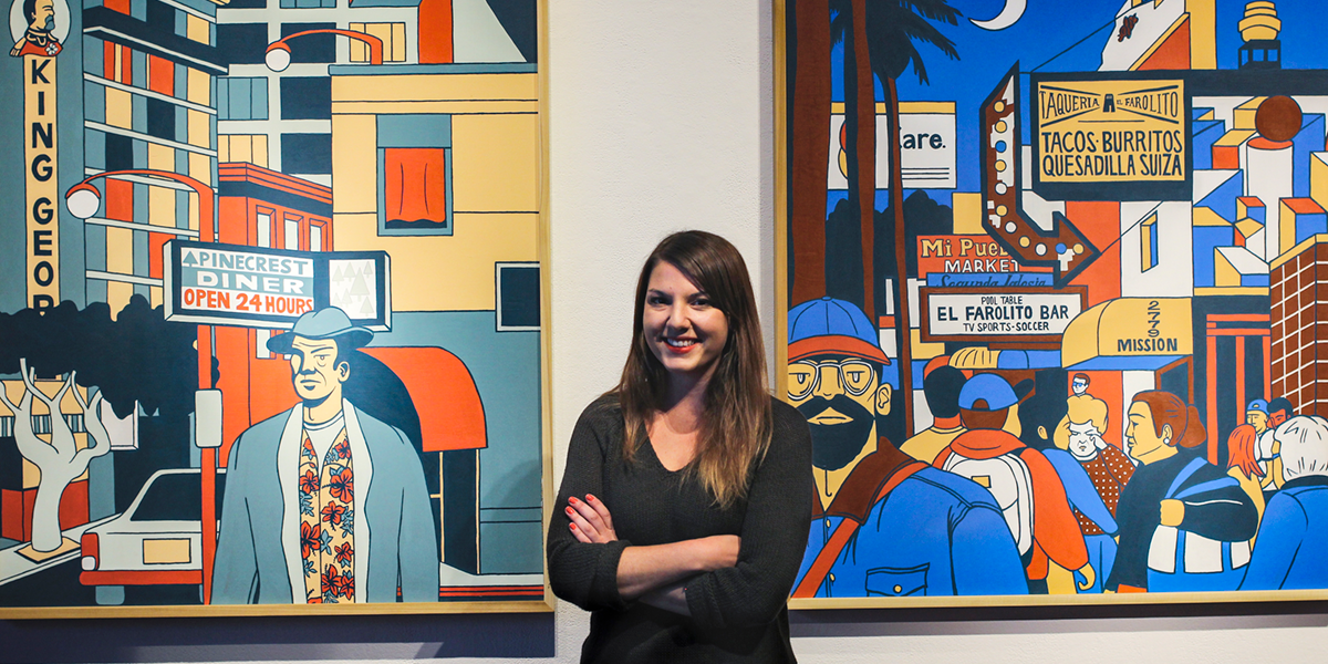 Photo of Emily Fromm standing in front of two of her paintings