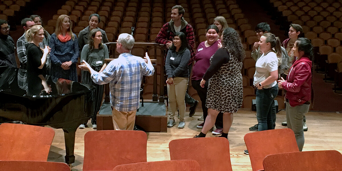 Photo of Professor David Xiques, conductor Gemma New and 15 students rehearsing at Davies Symphony Hall