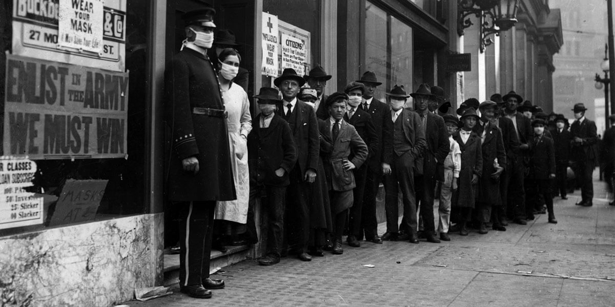 Black and white photo from 1918 of people waiting in line in San Francisco to get flu masks