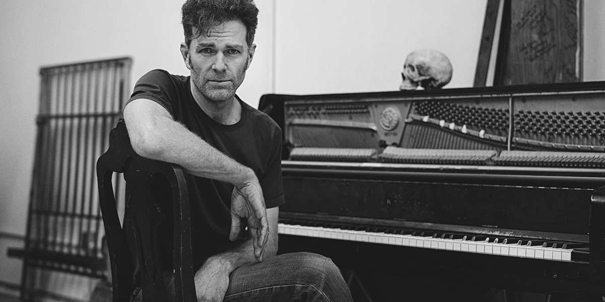 Black and white photo of Mark Jackson sitting at piano