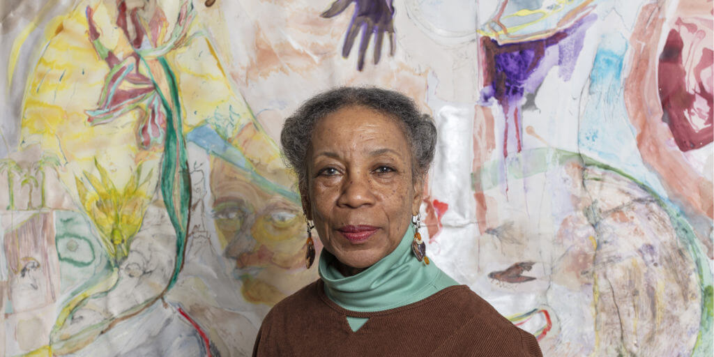 Photo of Suzanne Jackson standing in front of one of her paintings