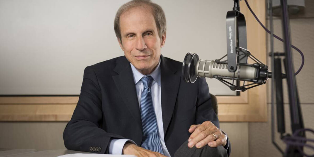 Michael Krasny seated in a studio next to a microphone