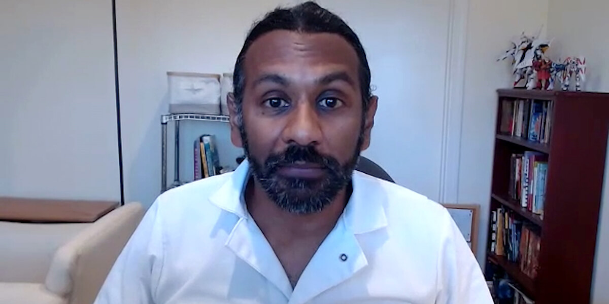 Mayuran Tiruchelvam speaks into a webcam while sitting in a home office