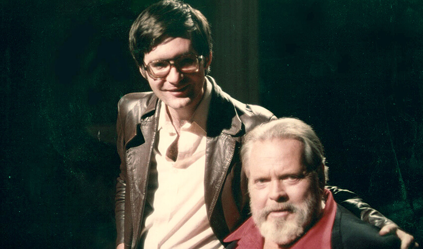 Archival photo of Joseph McBride with his arm around Orson Welles' shoulder