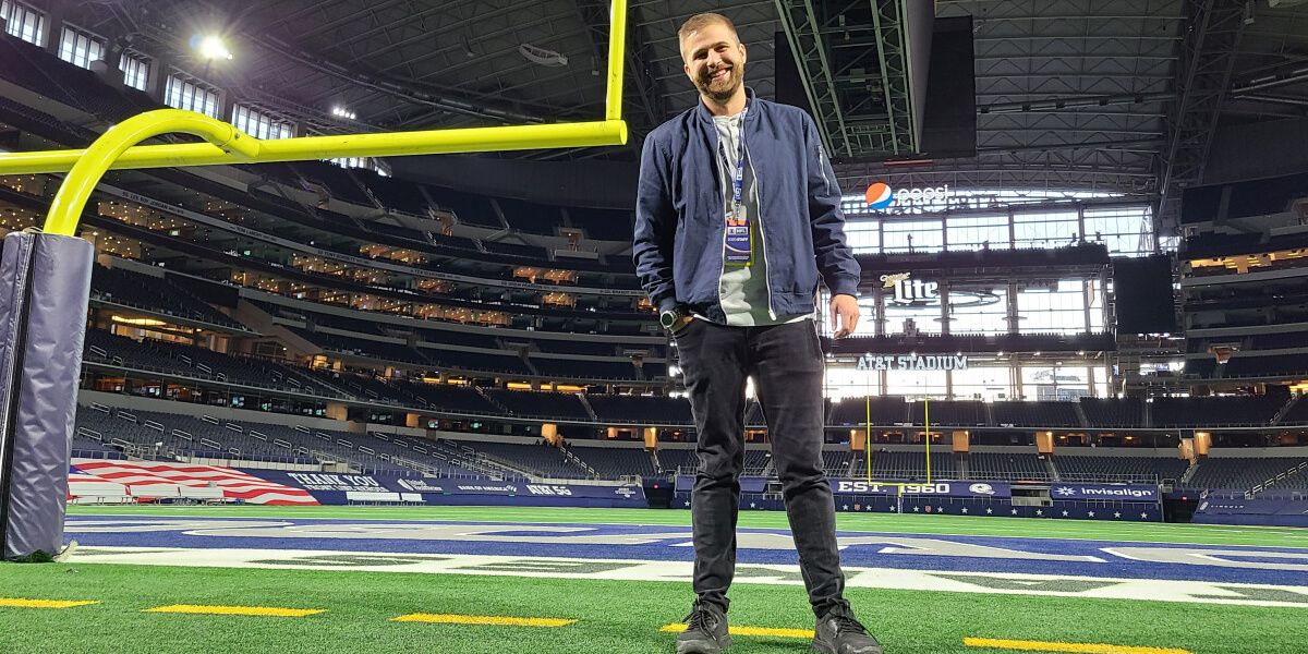 Travis McKinnon standing behind a goalpost on the field at AT&T Stadium in Dallas, Texas