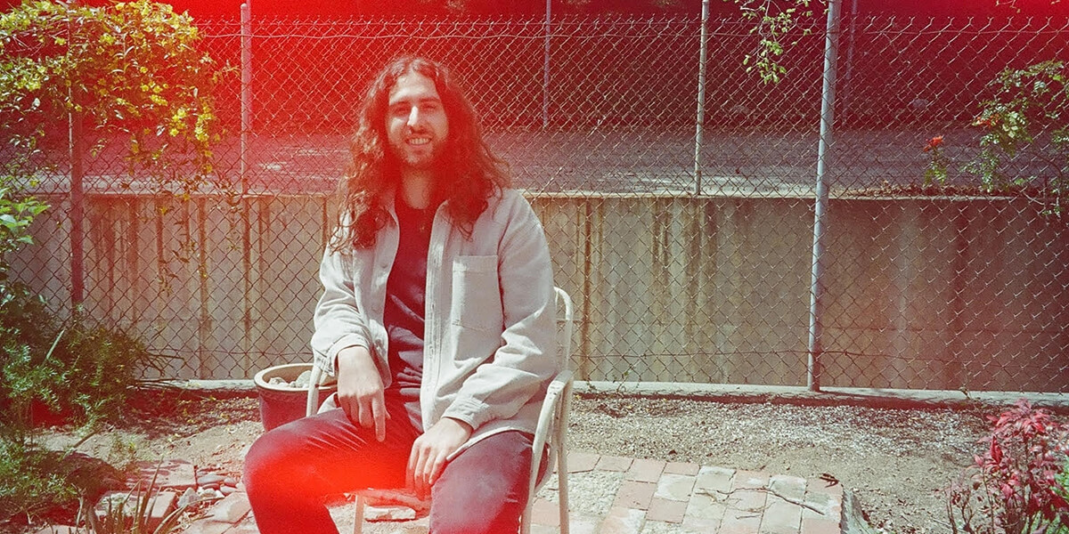 Nate Mercereau sitting in a backyard in front of a chain-link fence