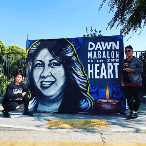 Photo of muralists posing next to mural honoring memory of Professor Dawn Mabalon