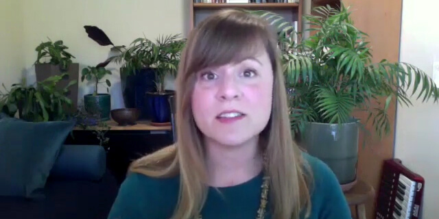 Photo of Jennifer Mylander speaking into webcam while seated with plants and a keyboard behind her