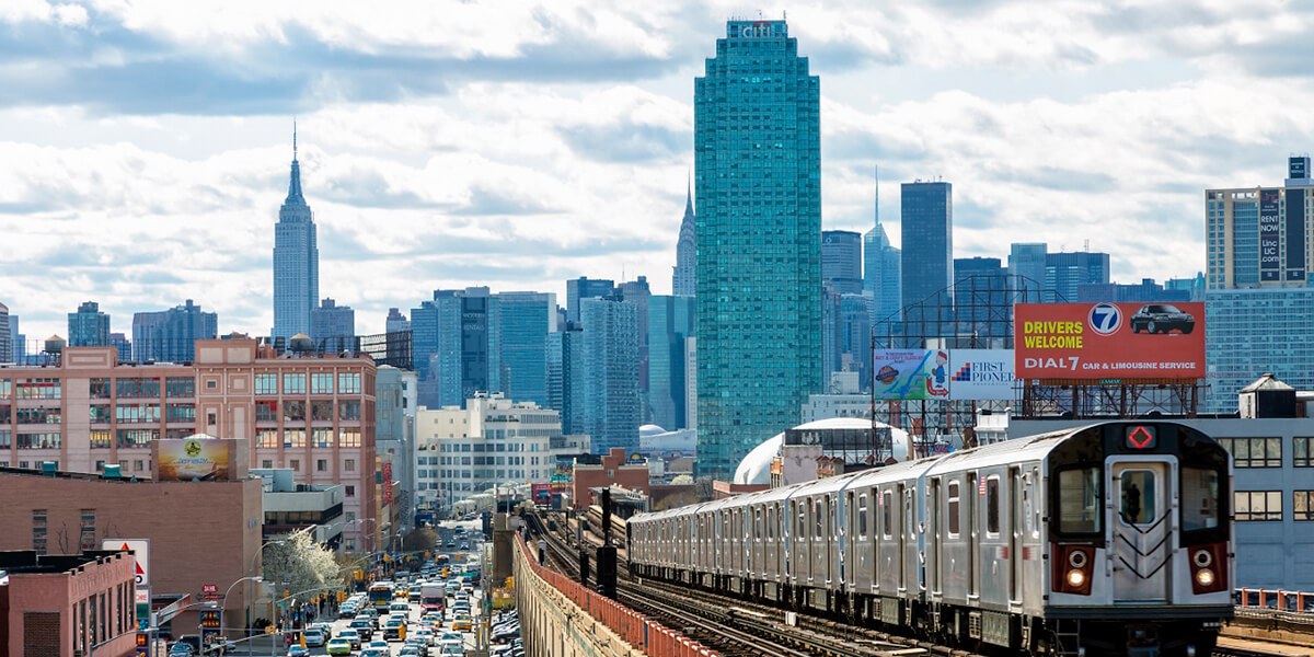Photo of elevated train in Queens County with New York City skyline in the background