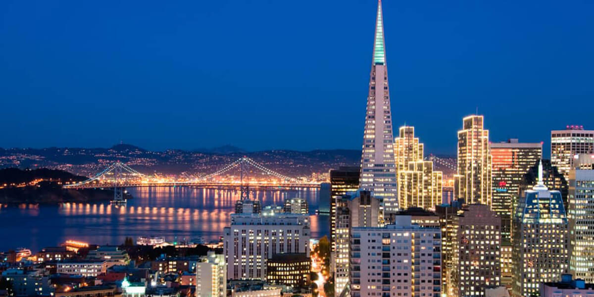 Nighttime photo of San Francisco skyline, Bay Bridge western span, Yerba Buena Island and Oakland Hills