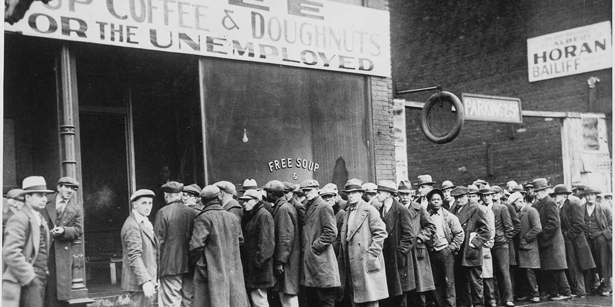 Black and white photo of Unemployed men standing in line outside a Great Depression soup kitchen opened in Chicago by Al Capone