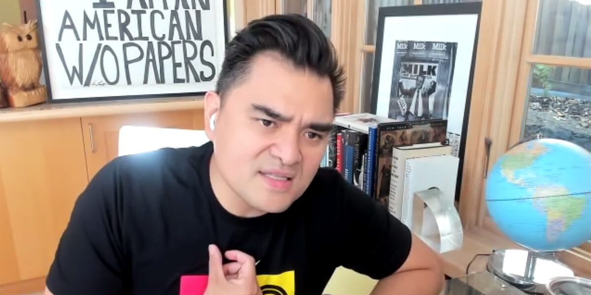 Screenshot image of Jose Antonio Vargas speaking into webcam while sitting at a desk in front of a framed drawing of the text I Am An American W/O Papers