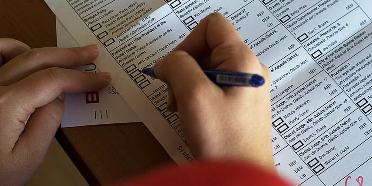 Close-up photo of hands using a felt-tip pen to mark ballot for 2008 U.S. presidential election