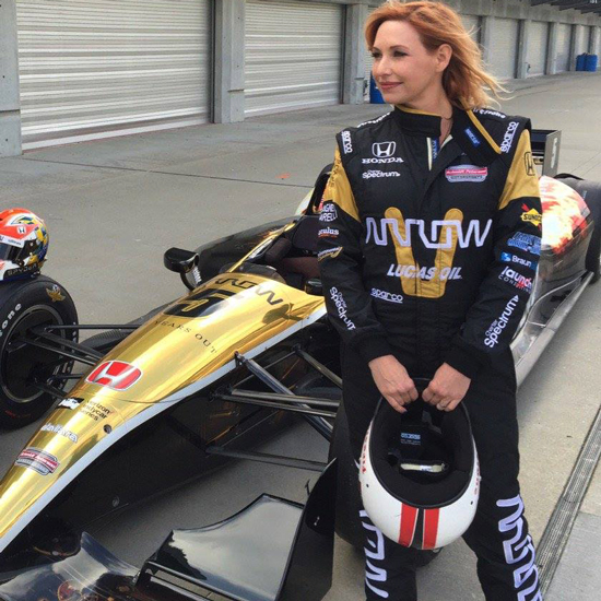 Photo of Kari Byron standing in front of a race car