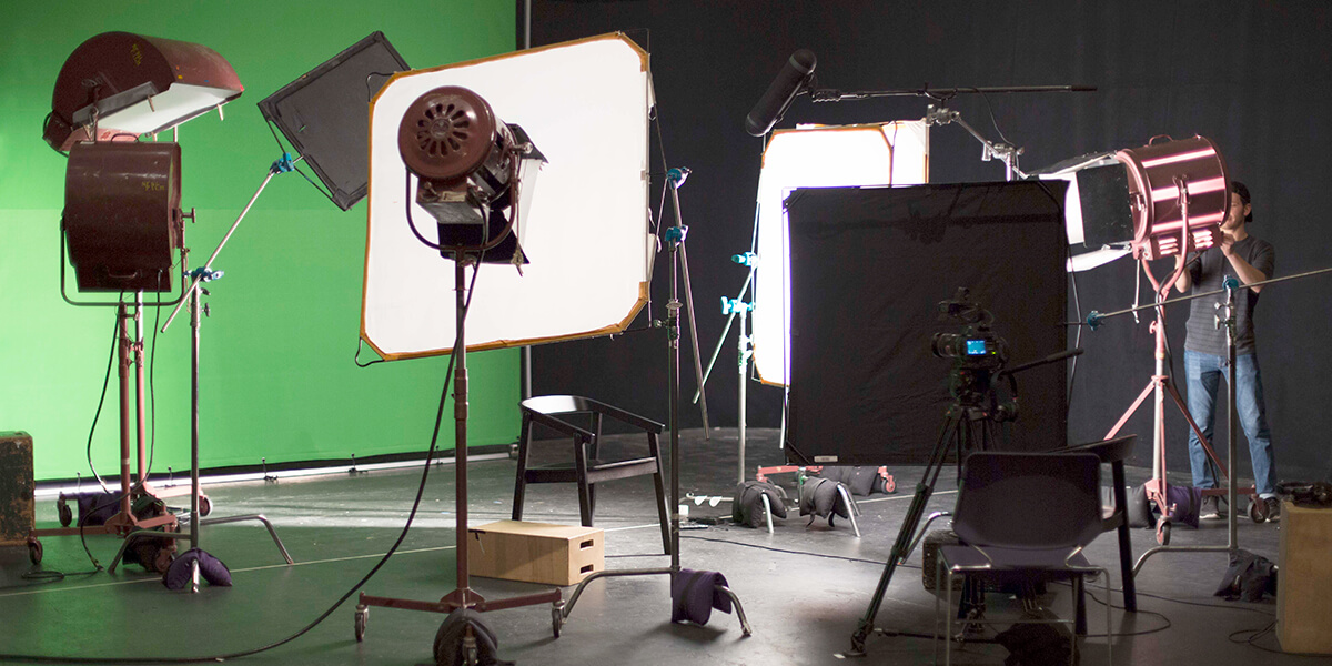 Photo of student adjusting lighting on indoor film set with green screen