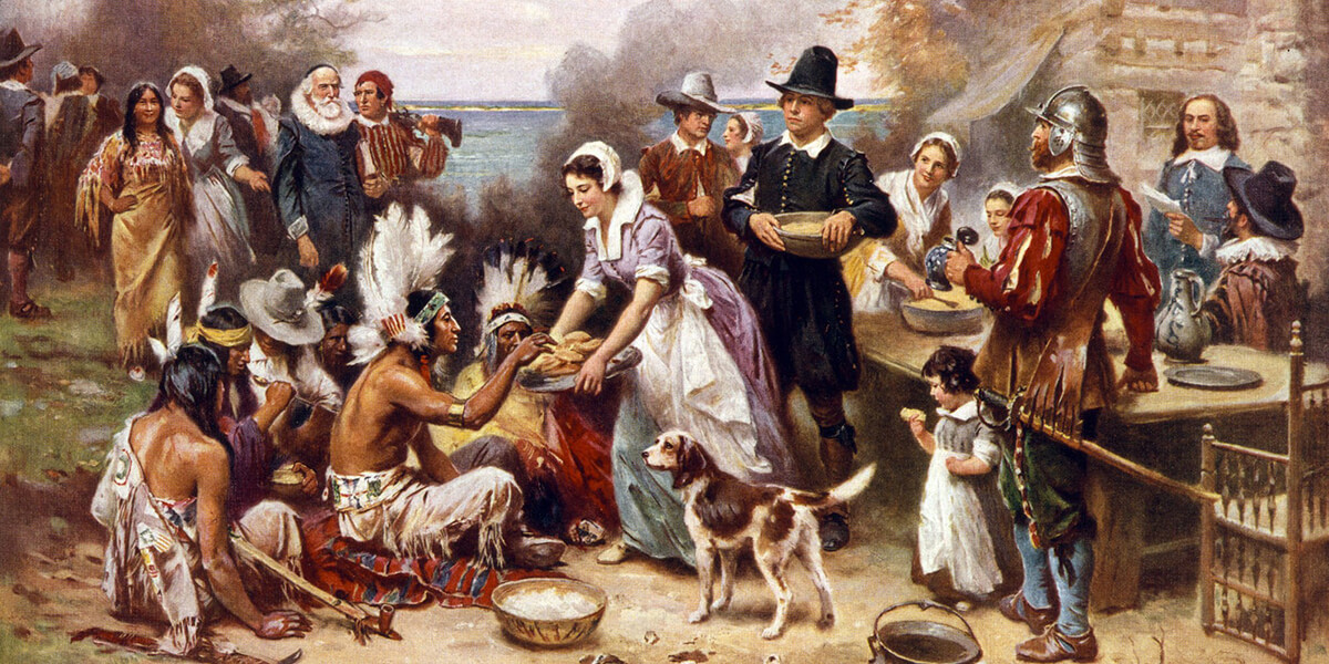 Painting of the first Thanksgiving showing pilgrims and Native Americans feasting together